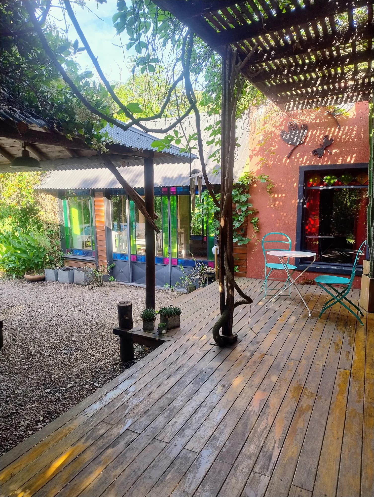 Galería exterior con ventanas de colores y vegetación