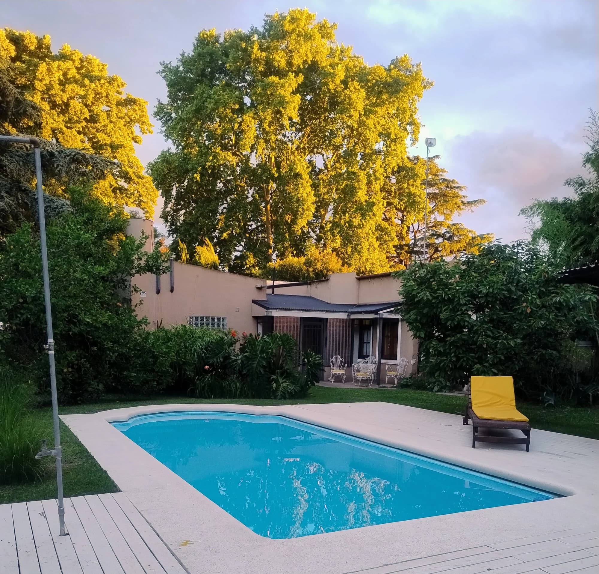 Pileta y jardín de El Vagón iluminados por el sol de la tarde