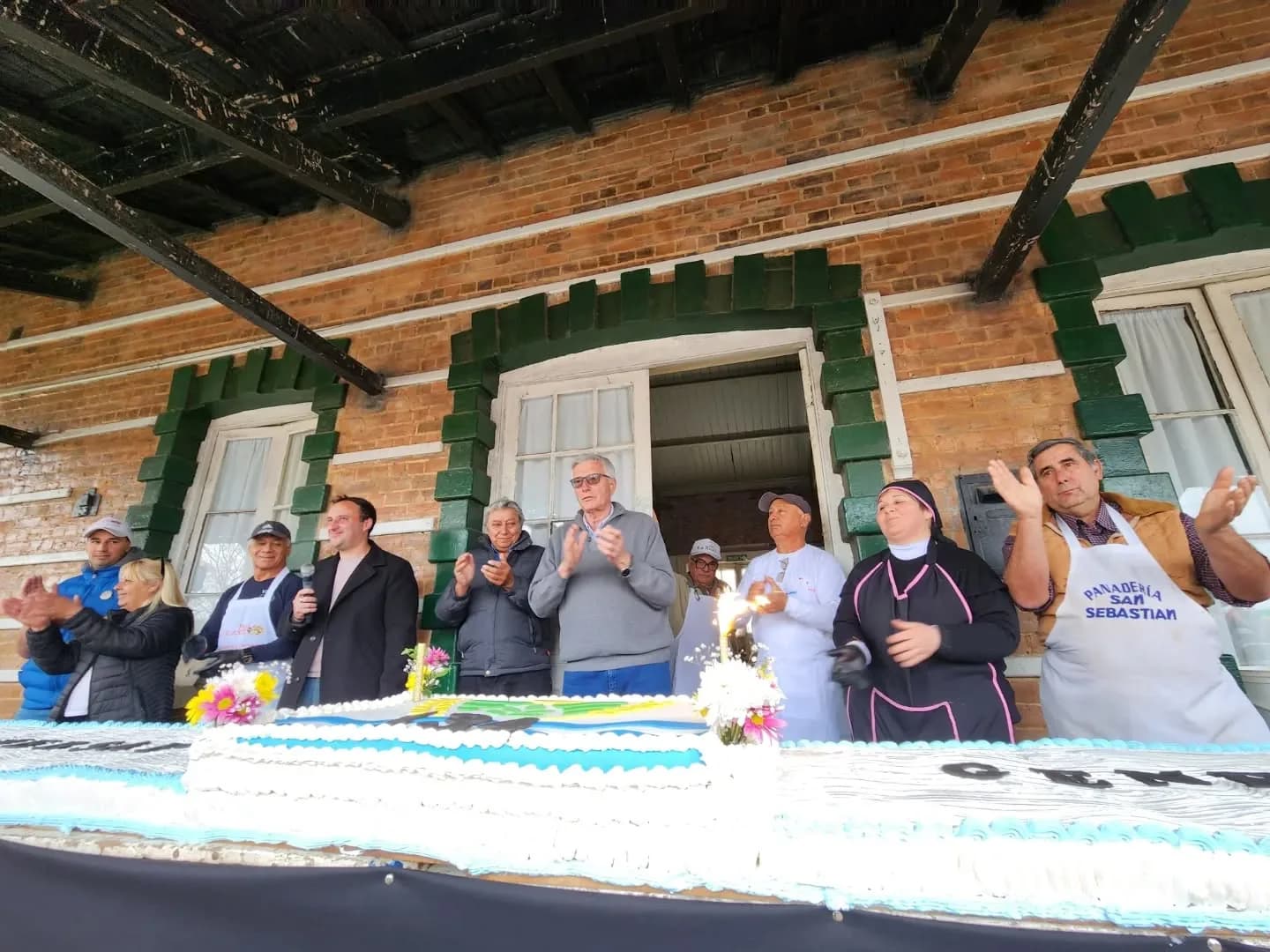 Vecinos cortando la gran torta durante el aniversario de General Belgrano